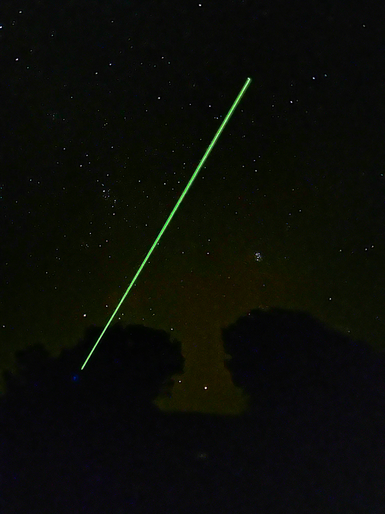 Green laser pointing to the night sky